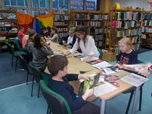 Dzieci siedzą przy stołach i wykonują prace plastyczne