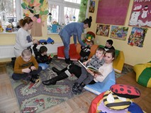 Dzieci siedzą na dywanie i oglądaja książki