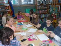 Dzieci siedzą przy stole i wykonują pracę plastyczna