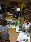 Bibliotekarka prezentuje dzieciom książki o dinozaurach
