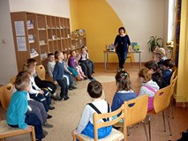 Bibliotekarka wita się z dziećmi, które siedzą na krzesełkach w kręgu