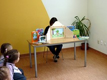 Teatrzyk Kamishibai - bibliotekarka czyta dzieciom historię żabki