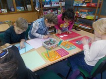 Dzieci siedzą przy stole i wykonuja prace plastyczne