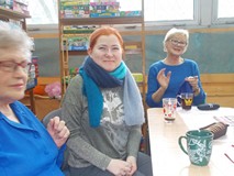 Bibliotekarka przymierza szal zrobiony przez jedną z uczestniczek spotkania