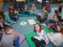 Dzieci wraz z bibliotekarką siedzą na materacach i rozmawiają o kompasach i znaczeniu kierunków po a