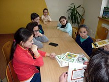 Moliki siedzą przy stoliku, bibliotekarki prezentują książki 