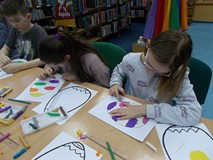 Dwie dziewczynki siedzą przy stole i ozdabiają jajka plasteliną