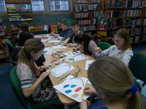 Dzieci siedzą przy stole i wykonują prace plastyczne