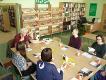 Uczestnicy spotkania siedzą przy stole i rozmawiają o książce