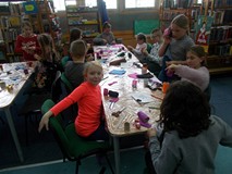 Dzieci siedzą przy stołach podczas zajęć plastycznych