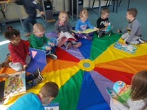 Dzieci siedzą na chuście i oglądają książki