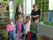 Bibliotekarka pokazuje dzieciom portfel wykonany z kartonu na mleko