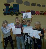 Kilkoro przedszkolaków dumnie prezentuje swoje rysunki