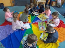 Dzieci siedzą na chuście i oglądają książki