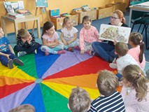 Dzieci oglądają wspólnie z bibliotekarką książkę