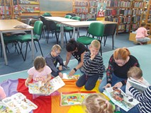 Dzieci wraz z bibliotekarką i nauczycielką oglądają książki