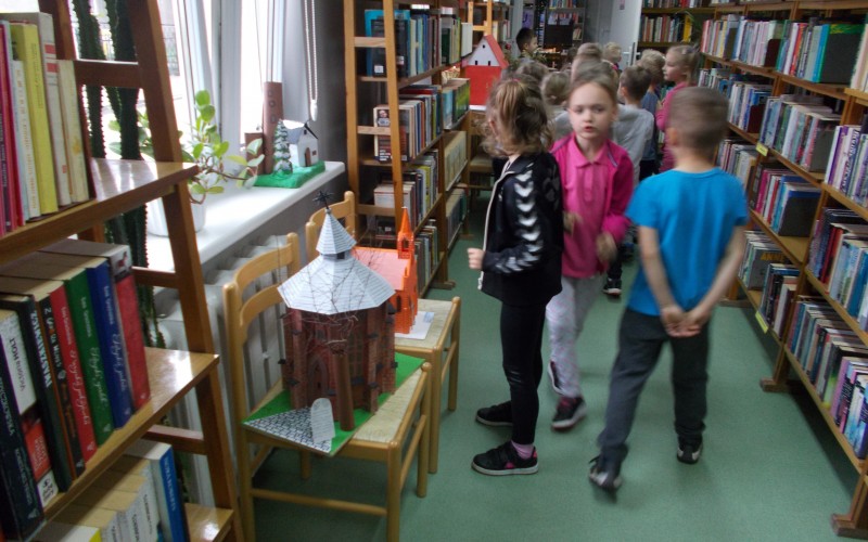 Kilkoro dzieci w bibliotecznej czytelni ogląda wystawę