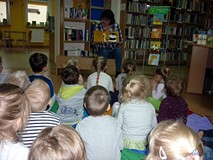 Bibliotekarka pokazuje dzieciom książeczkę z ilustrowanymi zagadkami