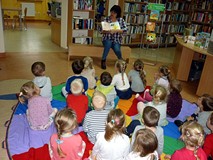 Bibliotekarka pokazuje dzieciom książeczkę z ilustrowanymi zagadkami