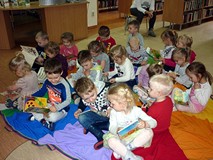 Dzieci siedzą na chuście integracyjunej i oglądają wybrane przez siebie książeczki