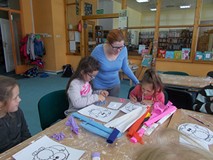 Bibliotekarka wspiera prace dwóch dziewczynek