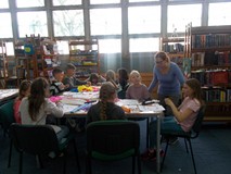 Dzieci wykonują prace plastyczne, a bibliotekarka obserwuje ich pracę