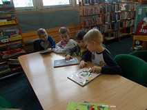 Dzieci siedzą przy stole i czytają książki