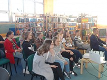 Młodzież siedzi na krzesłach i słucha wykładu