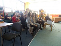 Młodzież siedzi na krzesłach i słucha wykładu