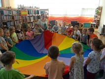 Dzieci wraz z bibliotekarką bawią się z chustą