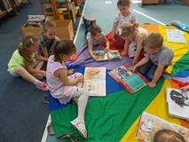 Dzieci siedzą na chuście i oglądają książki
