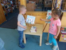 Dwoje dzieci wzięło do ręki książkę O dzieciach, które kochają książki z prośba by bibliotekarka mu 