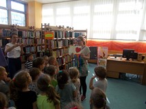 Bibliotekarka pozuje do zdjęcia z własnoręcznie wykonaną kartką z okazji Dnia Bibliotek i Biblioteka