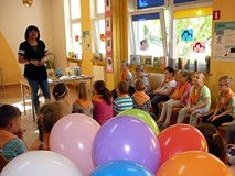 Bibliotekarka wita dzieci, które siedzą na krzesełkach