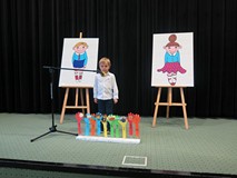 Chłopiec recytuje wiersz. Widzimy scenografię: Kolorowe ręce z brystolu trzymające różne przedmioty.