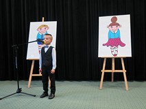 Cłopiec ubrany w czarną kamizelkę i spodnie recytuje wiersz