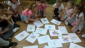 dzieci oglądają swoje prace plastyczne ułożone na podłodze