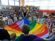 Dzieci wraz z bibliotekarką podczas zabawy z chustą
