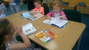 Dzieci siedzą przy stole i oglądają książeczkę