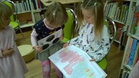 Dziewczynki oglądają interaktywną książeczke z użyciem kolorowych lupek