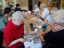 Panie siedzą przy stole i dyskutują o sztuce robienia na drutach