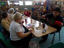 Panie siedzą przy stole i rozmawiają o sztuce rękodzielniczej