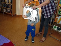 Zabawa z książką z dziurą - na zdjęciu chłopczyk udający słonia