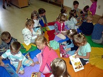 Dzieci siedzą na chuście integracyjnej i oglądają wybrane przez siebie książeczki