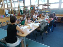 Dzieci siedza przy stołach podczas wykonywania prac plastycznych