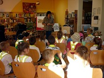 Kilka słów o herbach Koszalina - dzieci siedzą na krzesełkach i słuchają prowadzącej lekcję