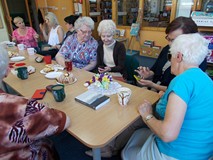 Panie siedzą przy stole i dyskutują o sztuce robienia na drutach