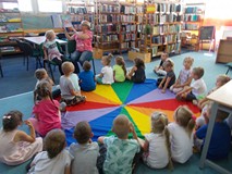 Zaproszony gość i mała czytelniczka pokazuje dzieciom ilustracje z książki