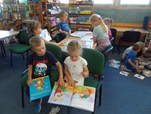 Dzieci siedzą przy stole i oglądają książeczki