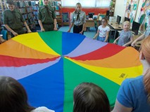 Harcerze wspólnie z dziećmi trzymają chustę animacyjną